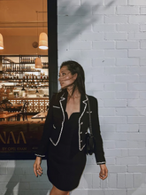 a lady wears a black tube mini dress with a black tweed jacket